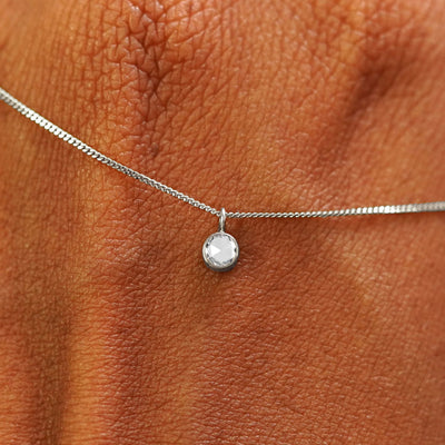 Close up view of a 14k white gold Rose Cut Diamond Necklace draped across the back of a model's hand
