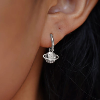 Close up view of a model's ear wearing a white gold Saturn Charm on a Curvy Huggie Hoop