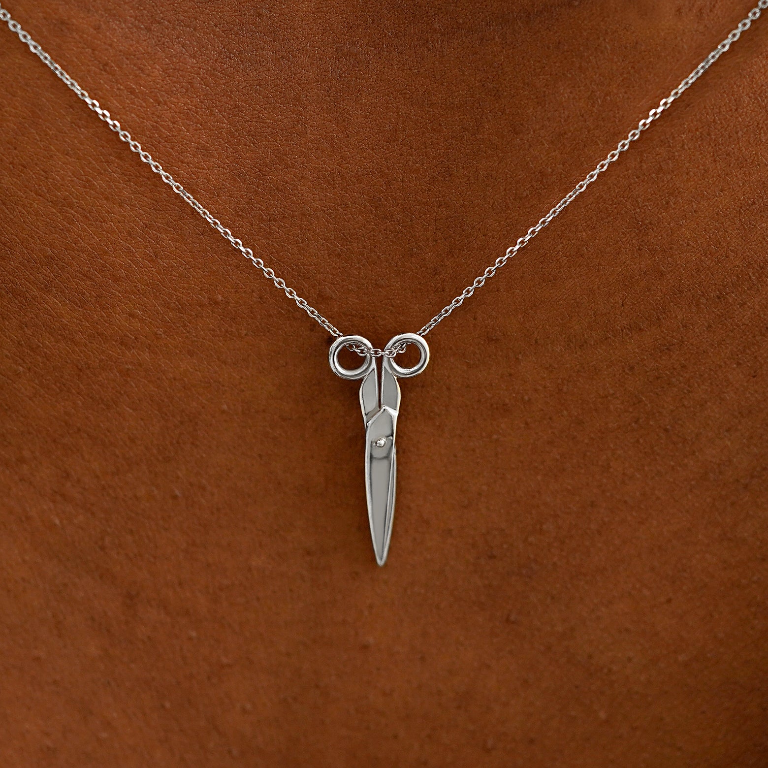 Close up view of a model's neck wearing a solid 14k white gold Scissors Necklace