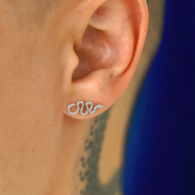 A model's ear wearing a 14k white gold Snake Earring with the snake horizontal