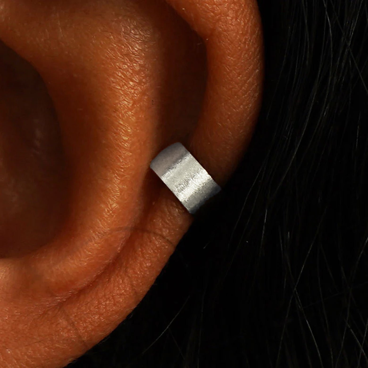 Close up view of a model's ear wearing a 14k white gold Stardust Thick Cuff