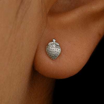 Close up view of a model's ear wearing a 14k white gold Strawberry Earring