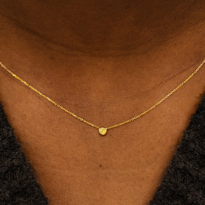 Close up view of a model neck wearing a 14k yellow gold Bezel set Yellow Diamond necklace 
