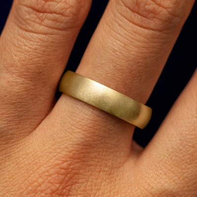 Close up view of a model's fingers wearing a 14k yellow gold Curvy Matte Band