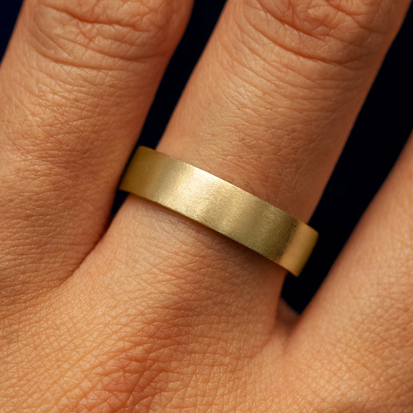 Close up view of a model's fingers wearing a 14k yellow gold Industrial Matte Band
