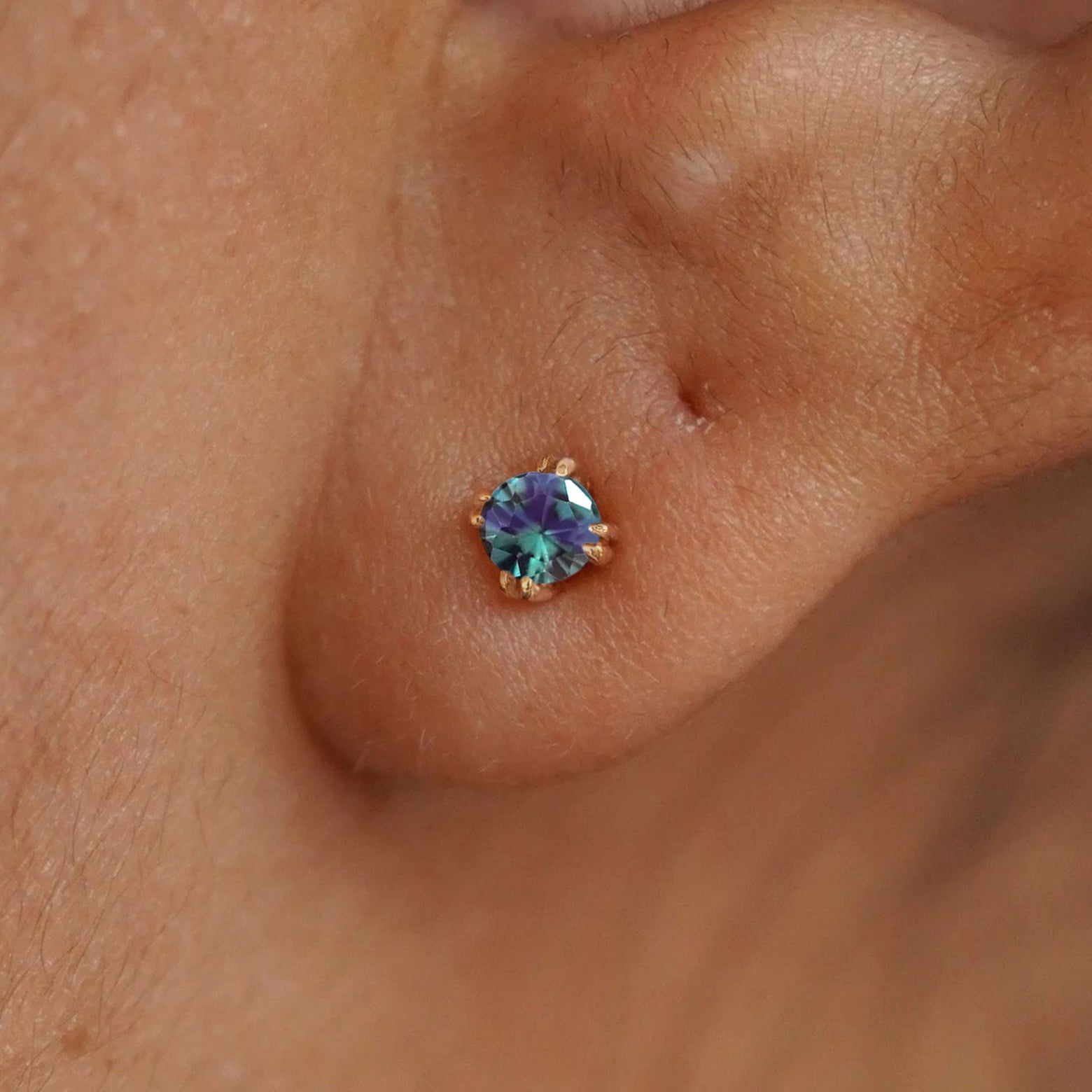 Close up view of a model's ear wearing a 14k yellow gold Alexandrite Stud Earring