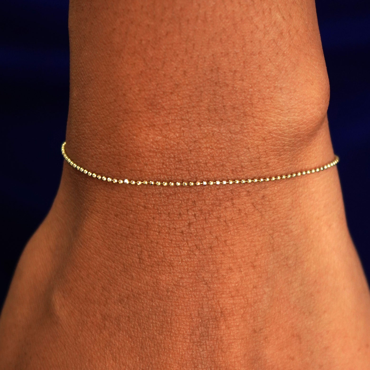 A model's wrist wearing a solid yellow gold Bead Bracelet