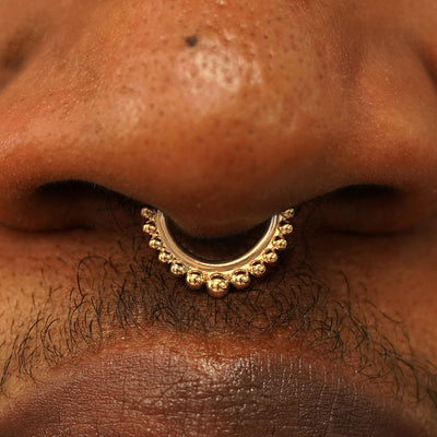 Close up view of a model's nose wearing a 14k yellow gold Beaded Septum