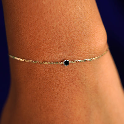 A model's wrist wearing a 14 karat yellow gold Black Diamond Bracelet