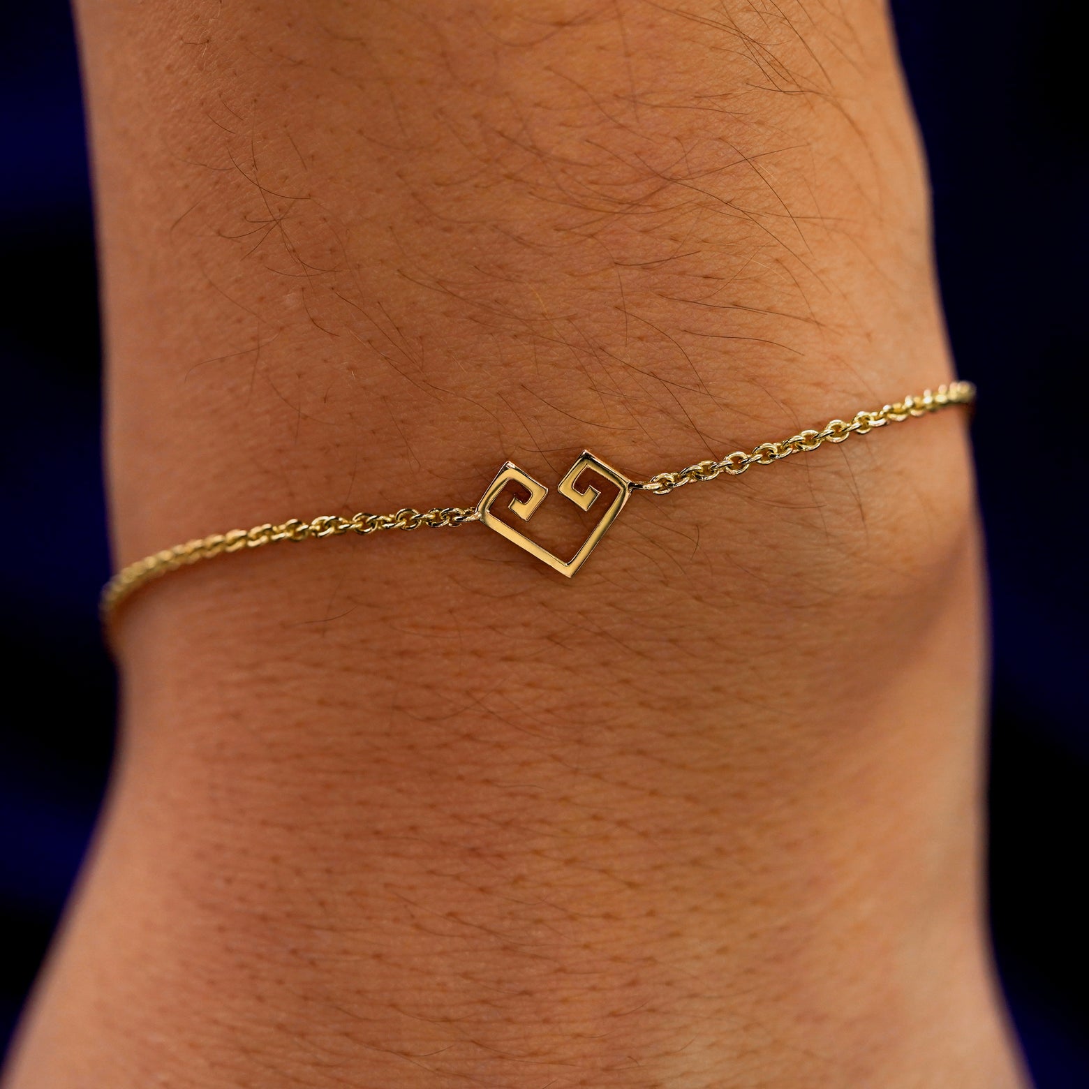 A close up view of a model's wrist wearing a yellow gold Chere Heart Bracelet