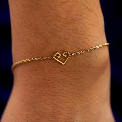 A close up view of a model's wrist wearing a yellow gold Chere Heart Bracelet