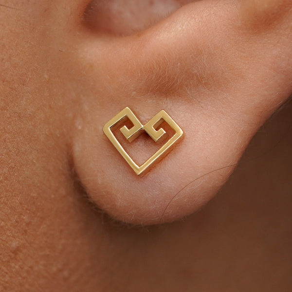 Close up view of a model's ear wearing a yellow gold Chere Heart Earring