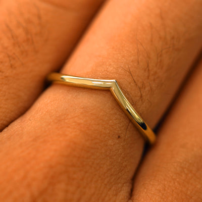 Close up view of a model's fingers wearing a 14k yellow gold mirror finish Chevron Band
