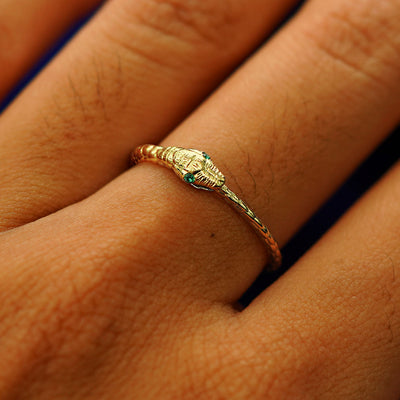 Close up view of a model's hand wearing a yellow gold emerald Gemstone Ouroboros Snake Ring