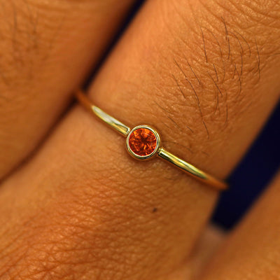 Close up view of a model's fingers wearing a 14k yellow gold Fire Opal Ring