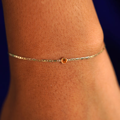 A model's wrist wearing a 14 karat yellow gold Fire Opal Bracelet
