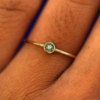Close up view of a model's fingers wearing a 14k solid yellow gold peridot gemstone ring