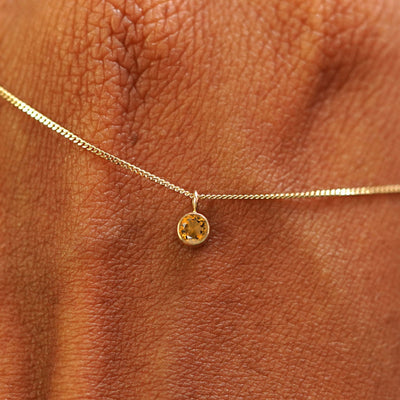 Close up view of a 14k yellow gold Citrine Necklace draped across the back of a model's hand
