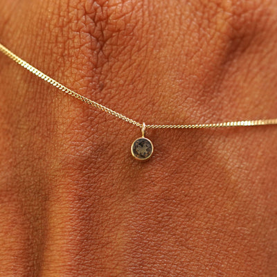 Close up view of a 14k yellow gold Smoky Quartz Necklace draped across the back of a model's hand