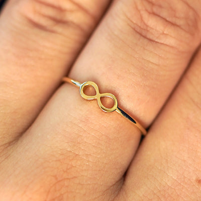Close up view of a model's fingers wearing a 14k yellow gold Infinity Ring