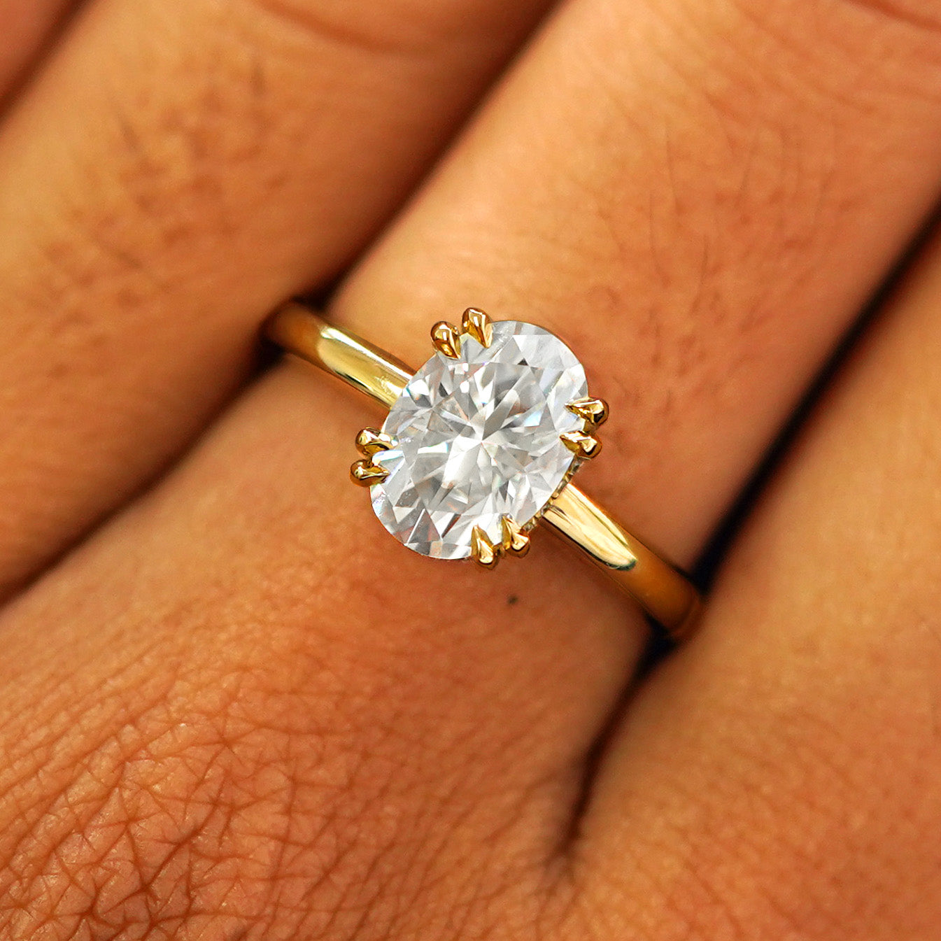 Close up view of a model's fingers wearing a 14k yellow gold Lab Diamond Halo Ring