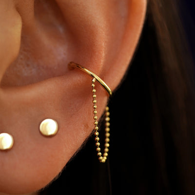 Close up view of a model's ear wearing a 14k yellow gold line cuff Earring