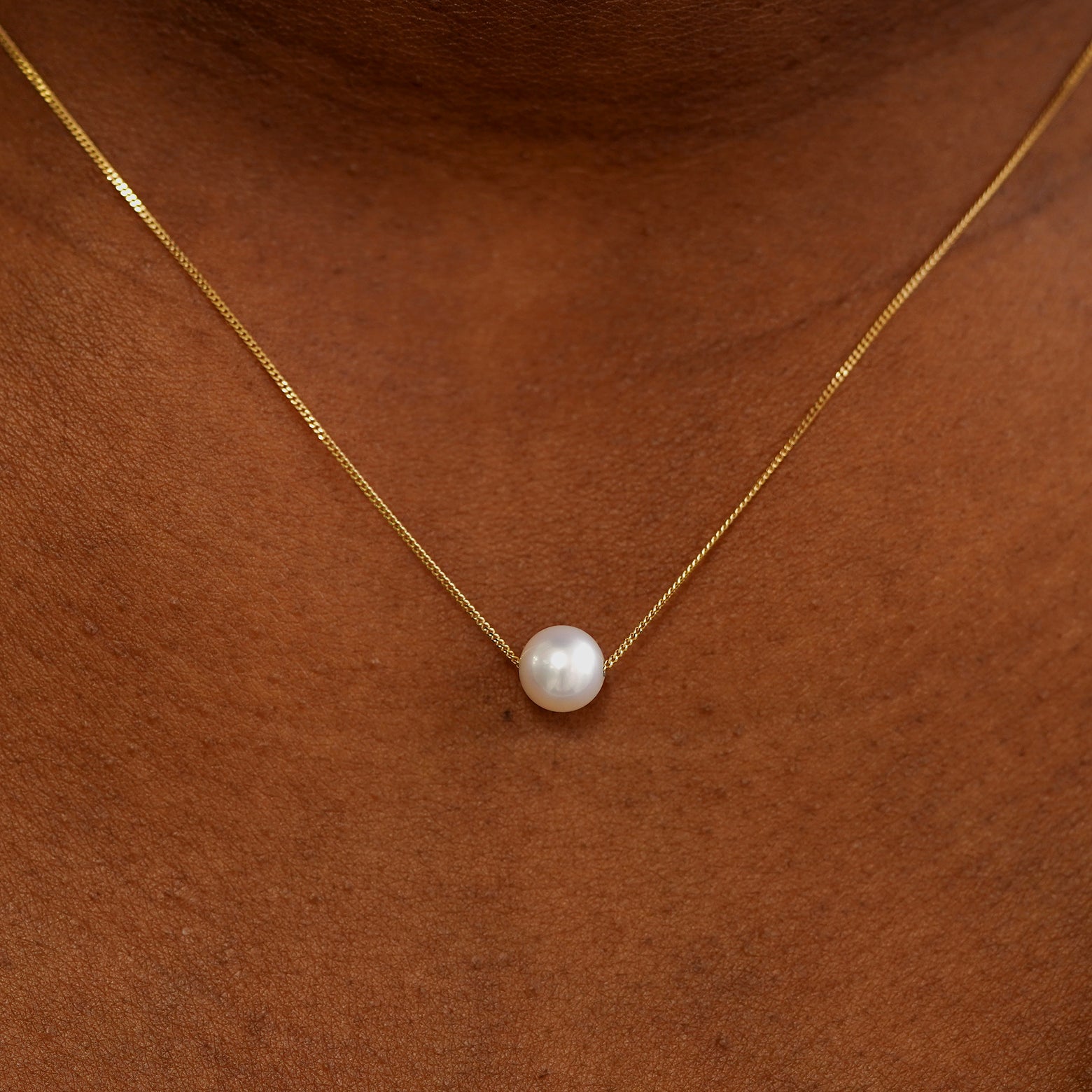 Close up view of a model's neck wearing a yellow gold Pearl Slide Necklace with a 6mm pearl