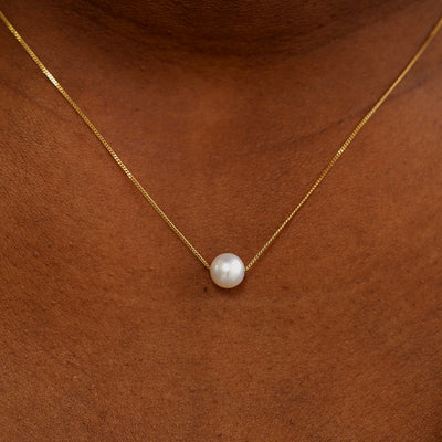 Close up view of a model's neck wearing a yellow gold Pearl Slide Necklace with a 6mm pearl