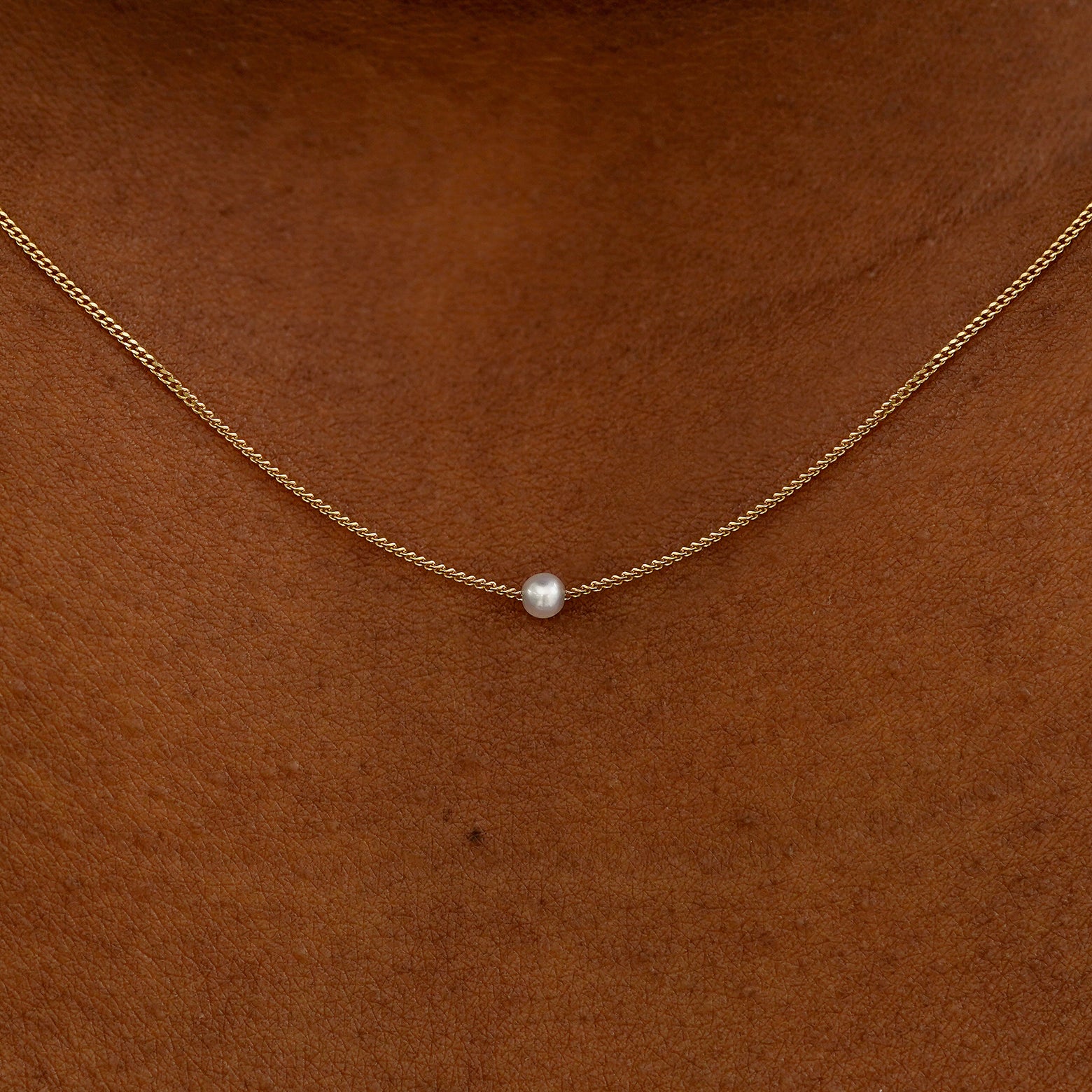 Close up view of a model's neck wearing a yellow gold Pearl Slide Necklace with a 2mm pearl