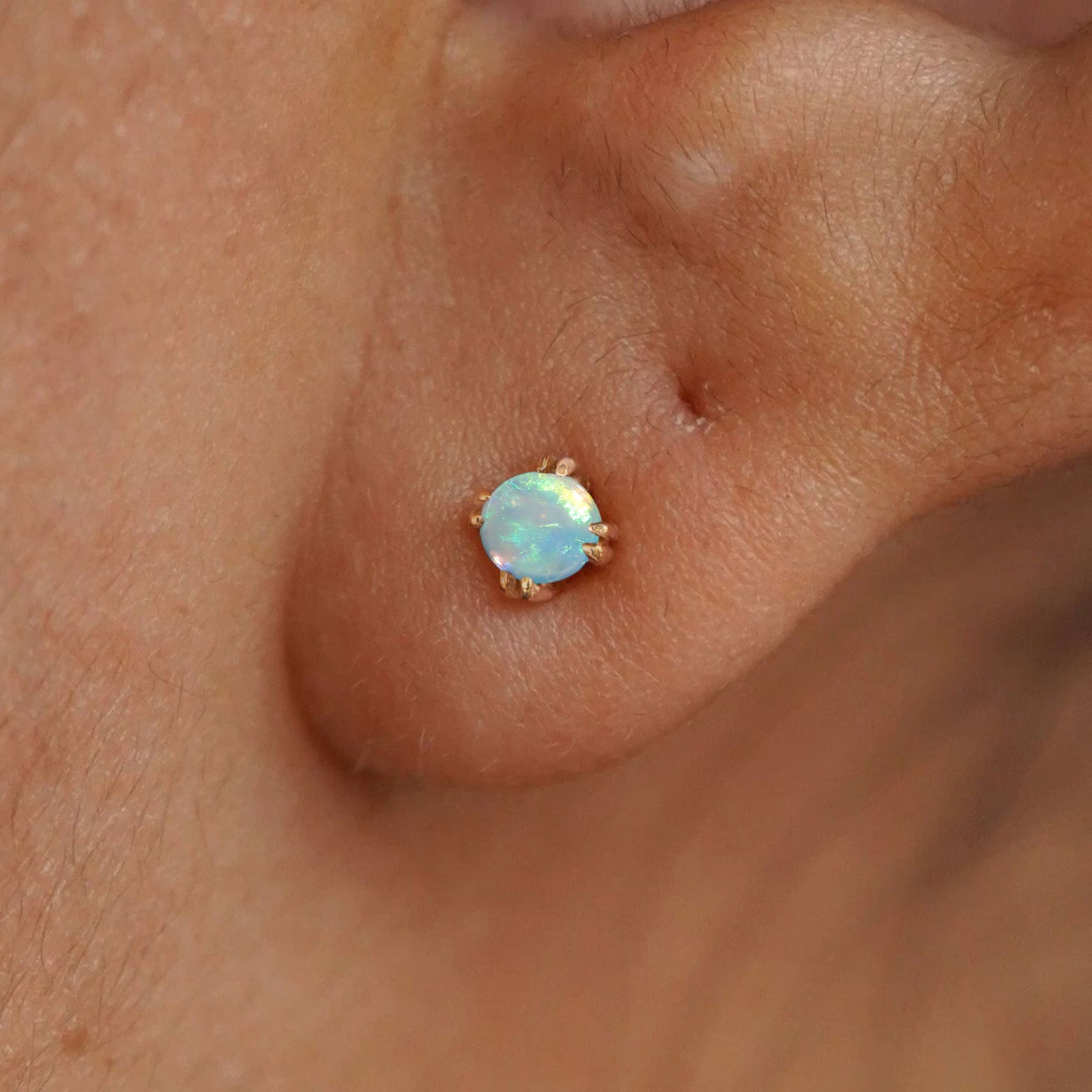 Close up view of a model's ear wearing a 14k yellow gold Opal Earring