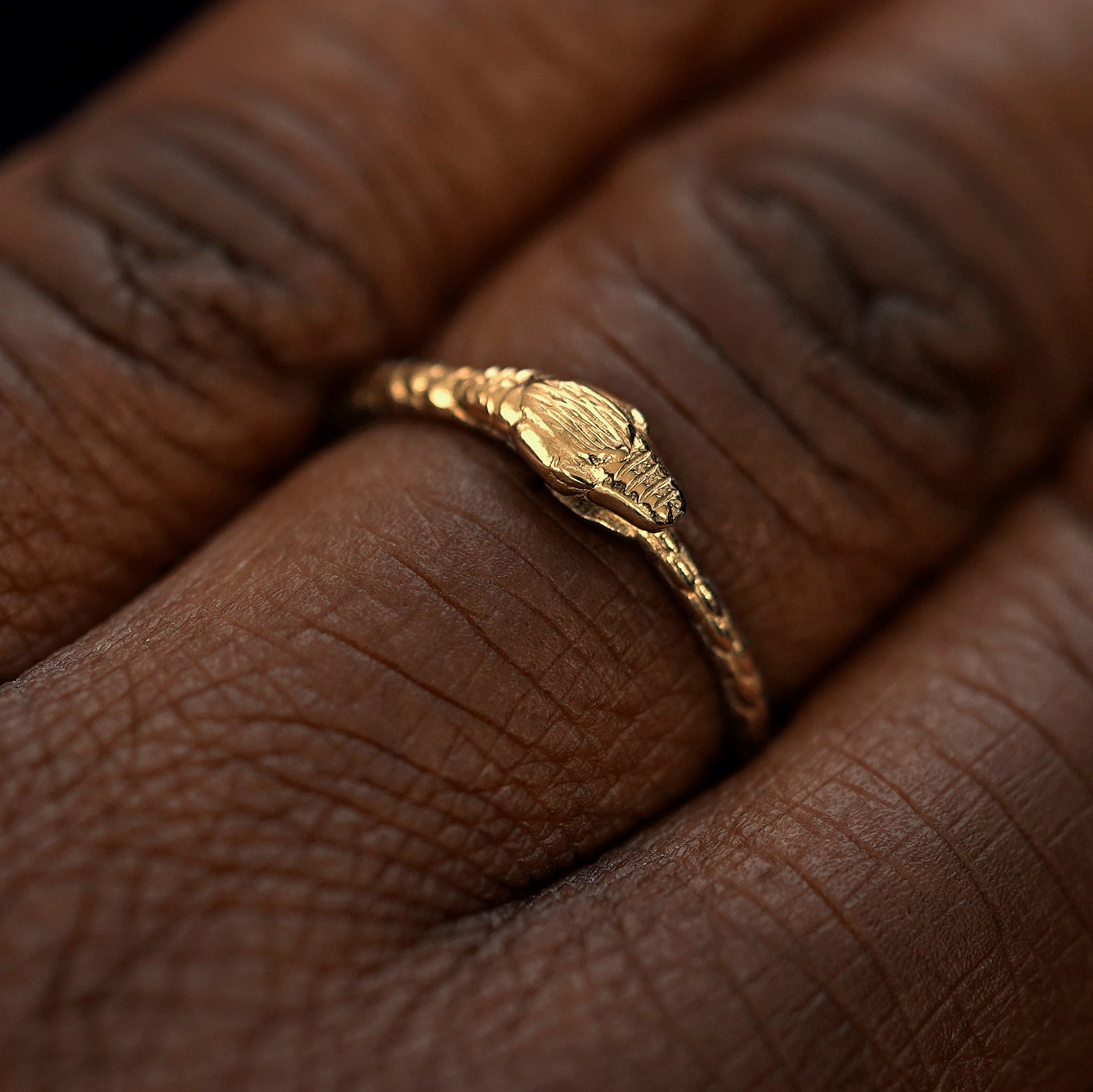Close up view of a model's hand wearing a yellow gold Ouroboros Snake Ring