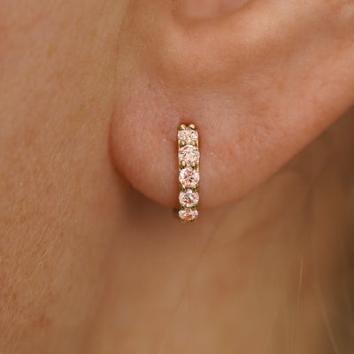Close up view of a model's ear wearing a yellow gold Mini Pink Lab Diamond Huggie Hoop