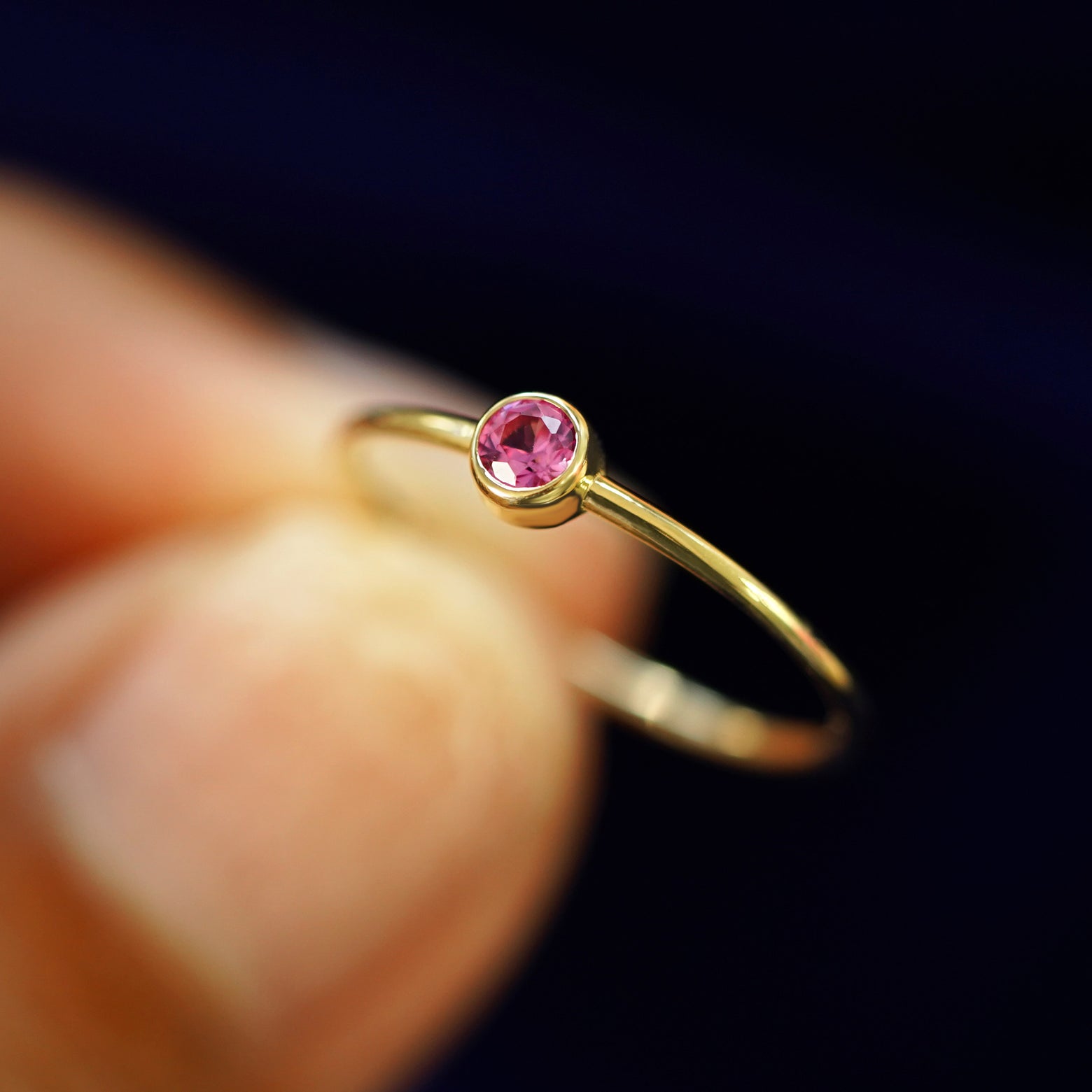 A model holding a Pink Sapphire Ring tilted to show the bezel setting