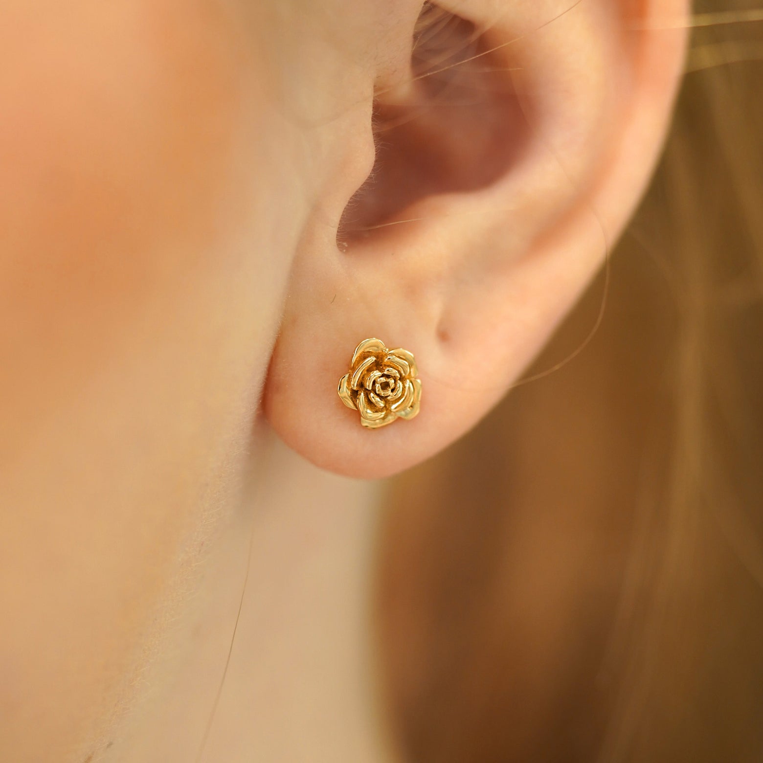 A model's ear wearing a 14k gold Rose Earring