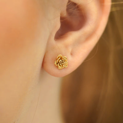 A model's ear wearing a 14k gold Rose Earring