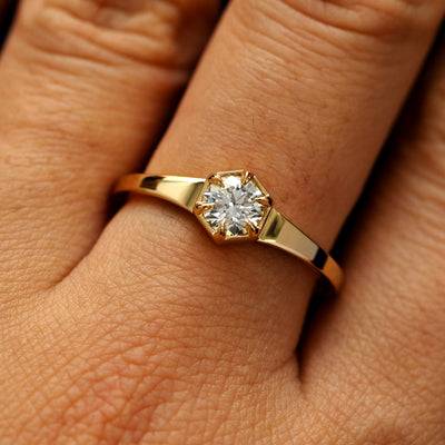 Close up view of a models fingers wearing a 14k yellow gold round diamond hexagon signet ring