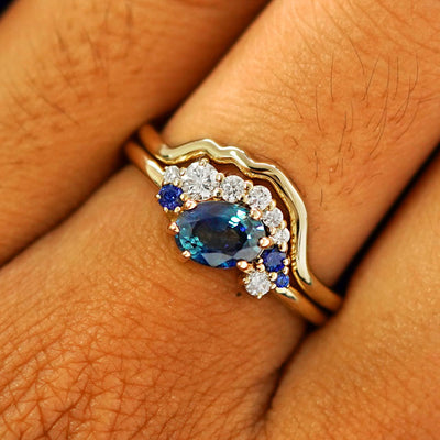 Close up view of a model's fingers wearing a 14k yellow gold Sapphire and Diamond Cluster Ring Set