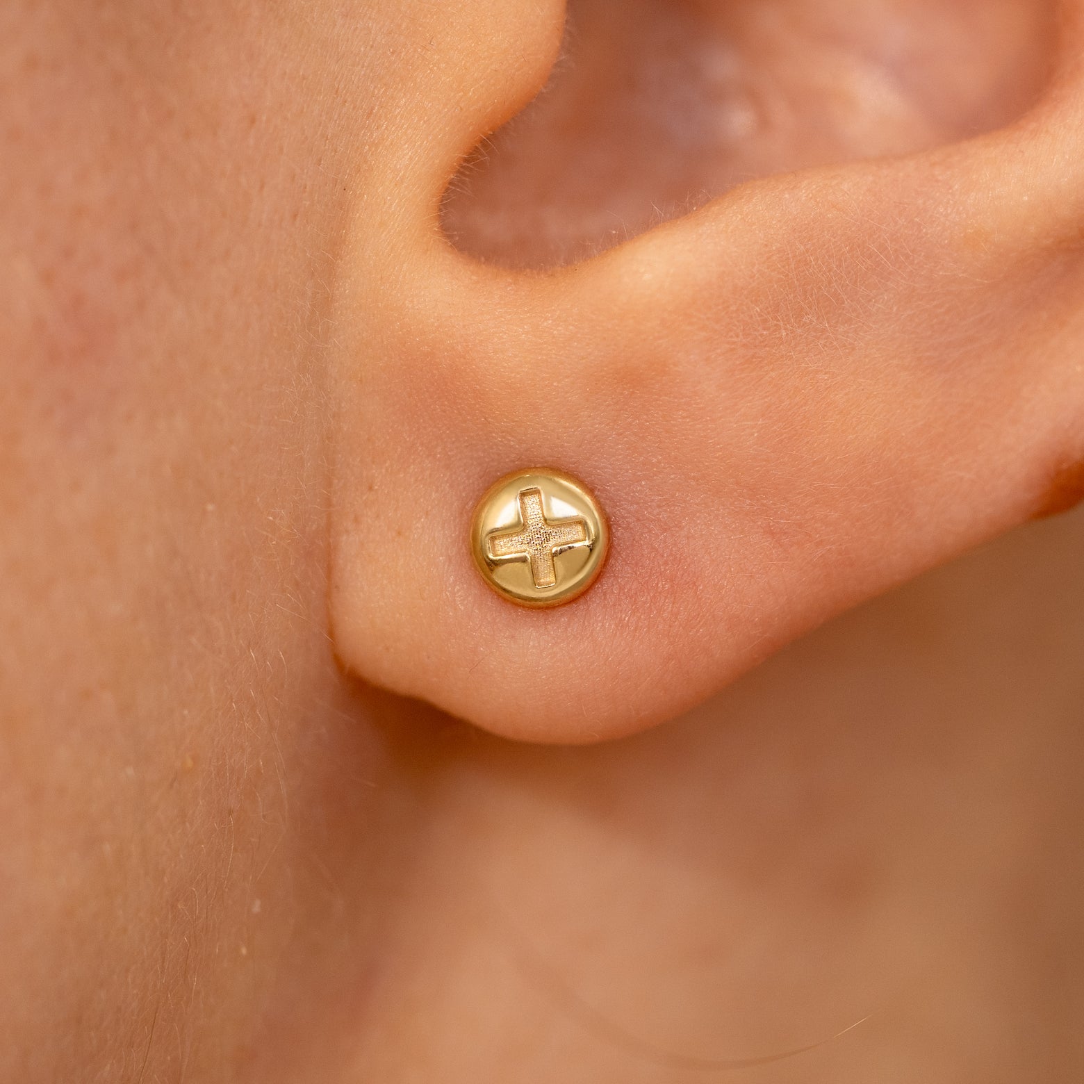 Close up view of a model's ear wearing a yellow gold Screw Earring