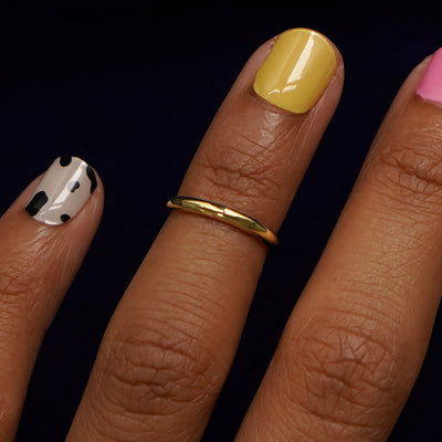 Close up view of a model's hand wearing a yellow gold Single Line Toe Ring as a midi ring