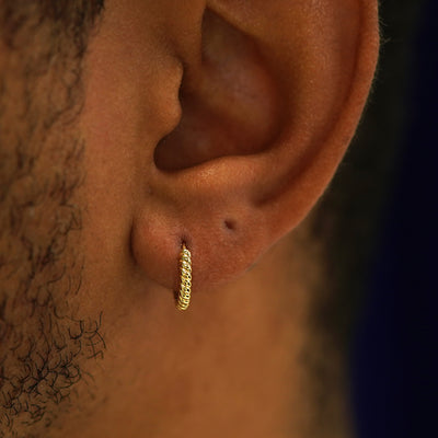A model's ear wearing a 14k yellow gold Small Rope Huggie Hoop Earring