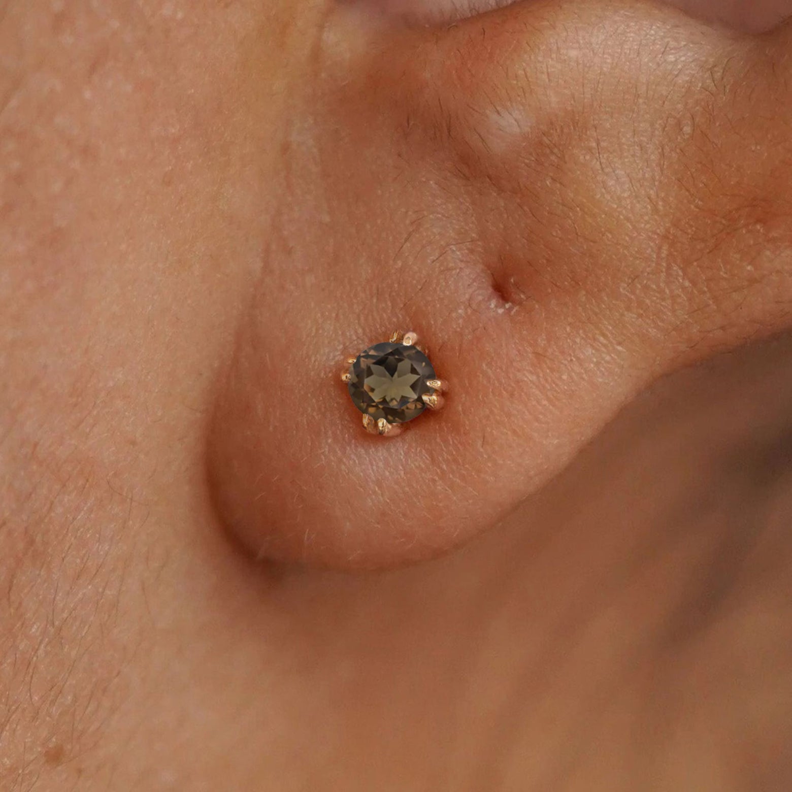 Close up view of a model's ear wearing a 14k yellow gold Rose Quartz Earring