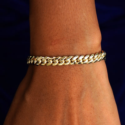 A model's wrist wearing a solid 14k yellow gold Miami Cuban Bracelet