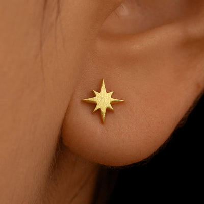 Close up view of a model's ear wearing a 14k yellow gold Starburst Earring
