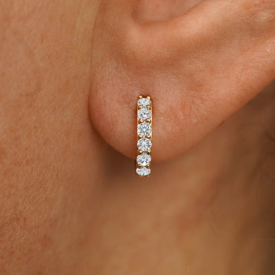 Close up view of a model's ear wearing a yellow gold Small White Lab Diamond Huggie Hoop