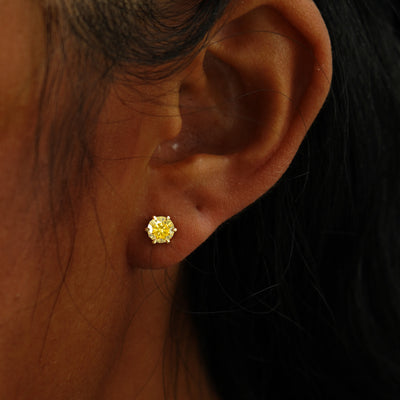 A model's ear wearing a 14k yellow gold yellow 5mm Moissanite Earring