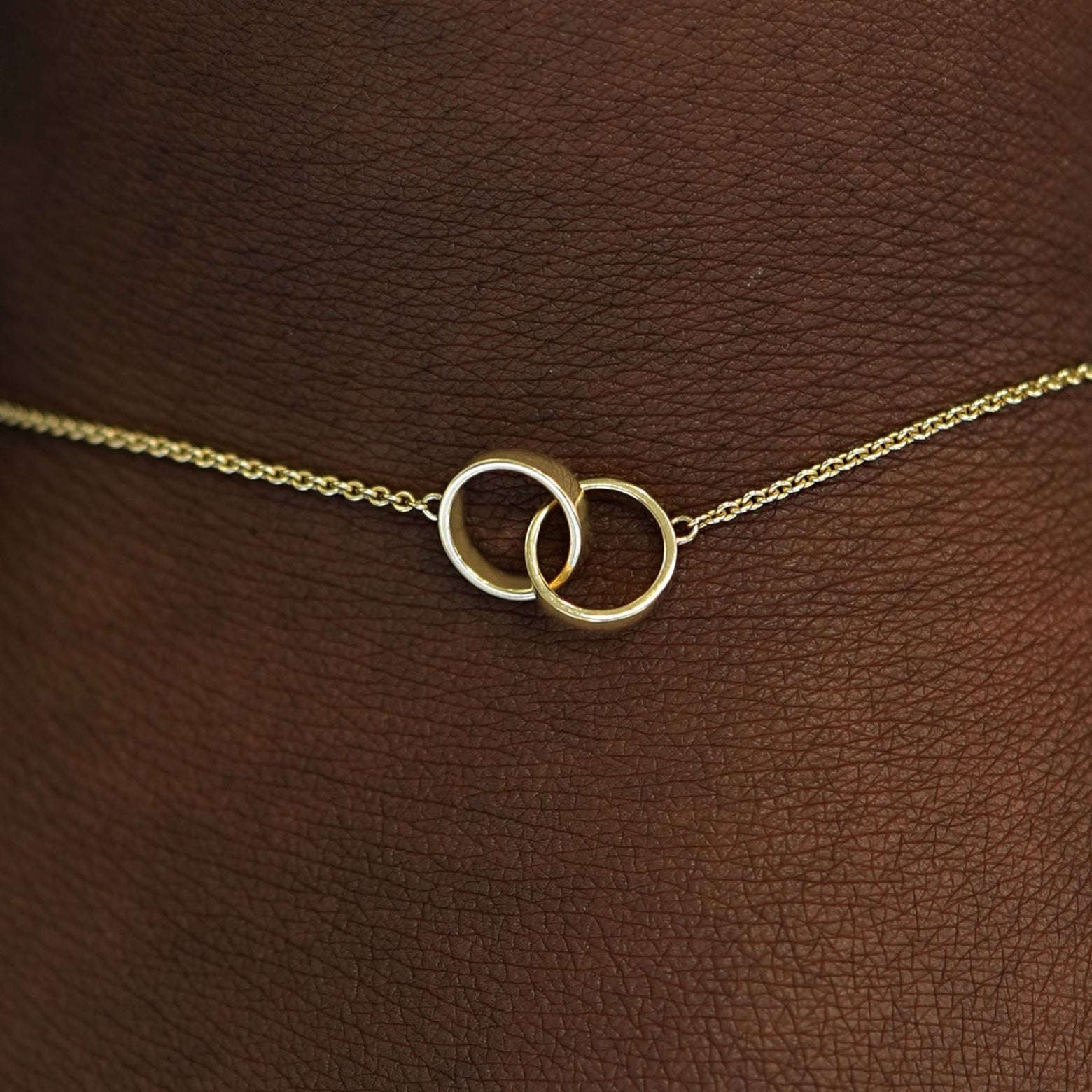 Close up view of a model's wrist wearing a solid gold Bound Together Bracelet