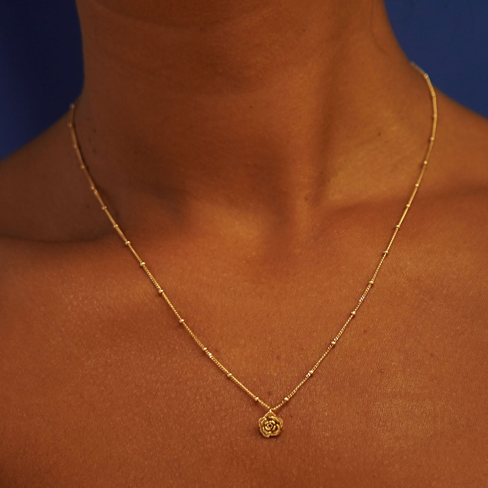 Close up view of a model's neck wearing a yellow gold Rose Charm on a Beaded Essential Chain