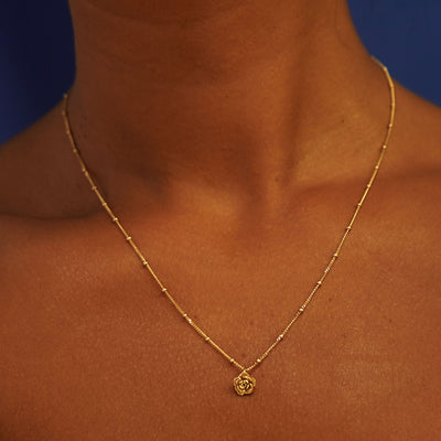 Close up view of a model's neck wearing a yellow gold Rose Charm on a Beaded Essential Chain