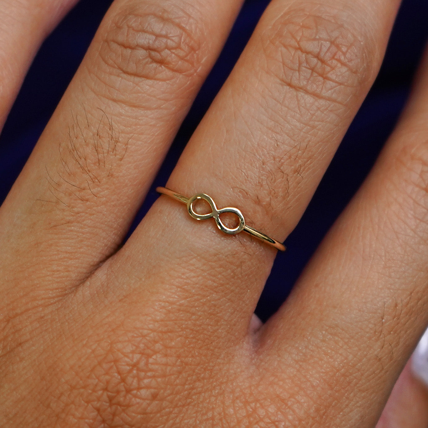 Close up view of a model's hand wearing a yellow gold Infinity Ring
