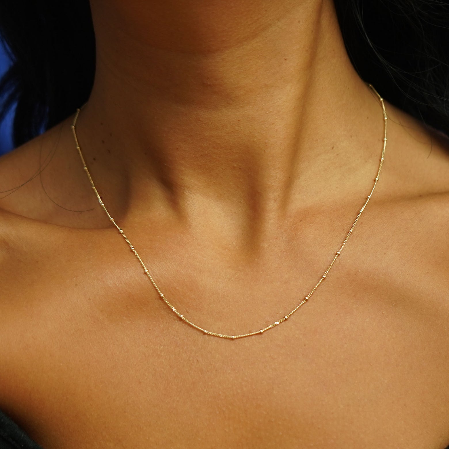 Close up view of a model's neck wearing a yellow gold Beads Chain